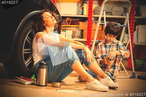 Image of resting mechanic woman and boy with thermos