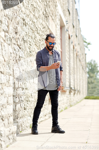 Image of man texting message with smartphone on city street