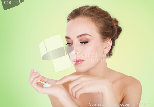 Image of happy young woman with moisturizing cream on hand