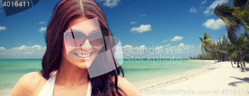 Image of smiling young woman with sunglasses on beach