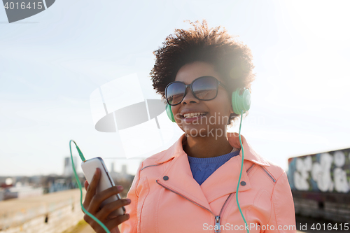 Image of happy young woman with smartphone and headphones