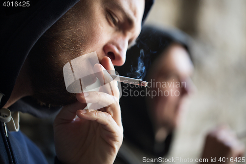 Image of close up of young man smoking cigarette outdoors