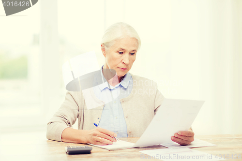 Image of senior woman with papers and calculator at home