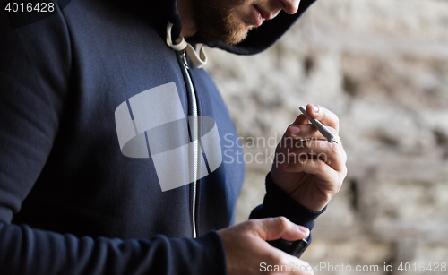 Image of close up of addict lighting up marijuana joint