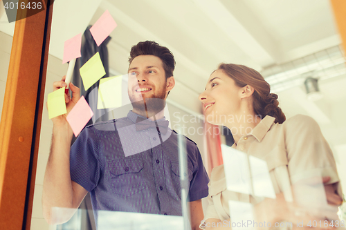 Image of creative team with stickers on glass at office