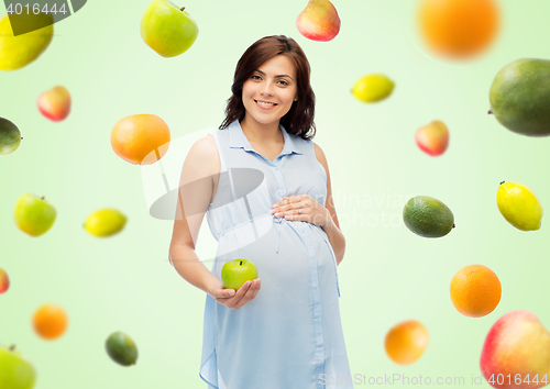 Image of happy pregnant woman holding green apple