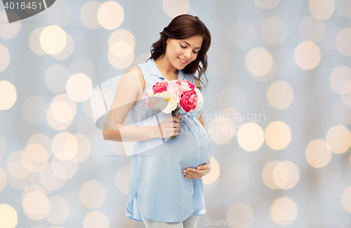 Image of happy pregnant woman with flowers touching belly