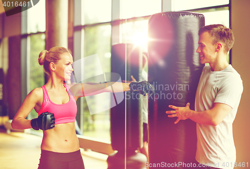 Image of smiling woman with personal trainer boxing in gym