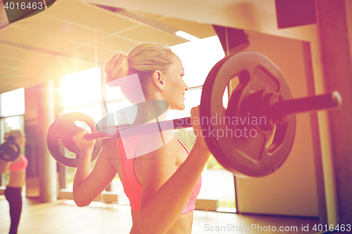 Image of sporty woman exercising with barbell in gym