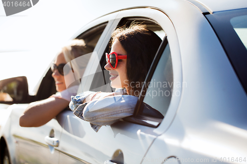 Image of happy teenage girls or women in car at seaside