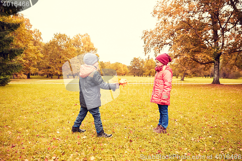 Image of little boy giving autumn maple leaves to girl