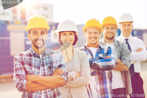 Image of group of smiling builders in hardhats outdoors