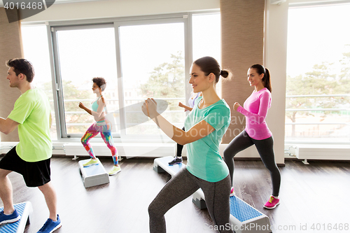 Image of group of people exercising on steppers in gym