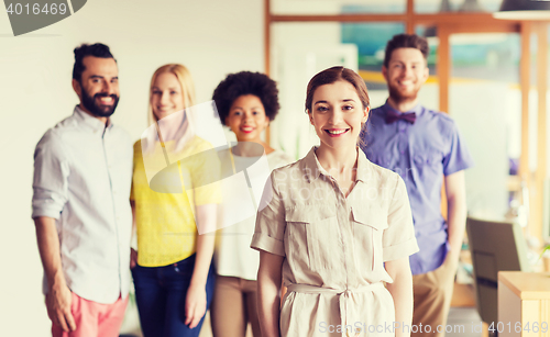 Image of happy young woman over creative team in office