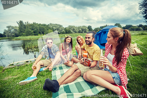 Image of happy friends with drinks and guitar at camping
