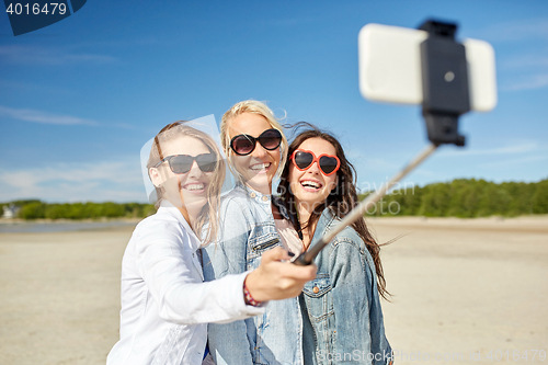 Image of group of smiling women taking selfie on beach