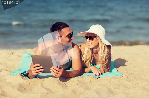 Image of happy couple with tablet pc sunbathing on beach