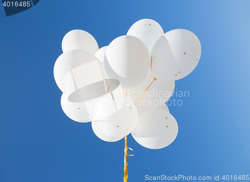 Image of close up of white helium balloons in blue sky