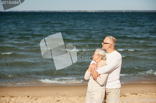 Image of happy senior couple hugging on summer beach
