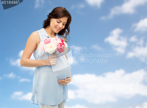 Image of happy pregnant woman with flowers touching belly