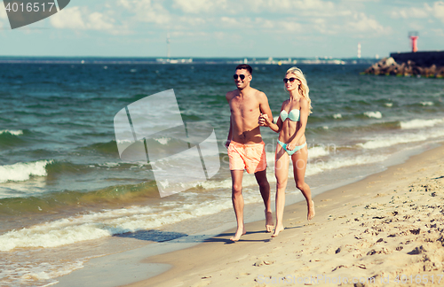 Image of happy couple in swimwear running on summer beach