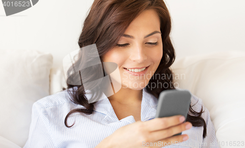 Image of happy woman with smartphone at home