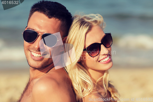 Image of happy couple in swimwear sitting on summer beach