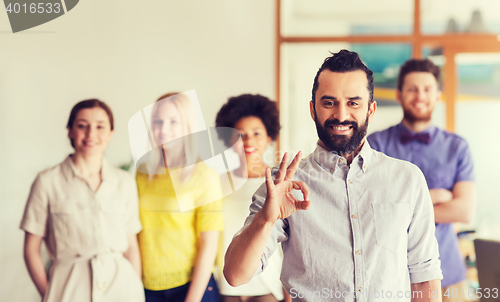 Image of happy young man over creative team in office