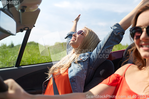 Image of smiling young women driving in cabriolet car