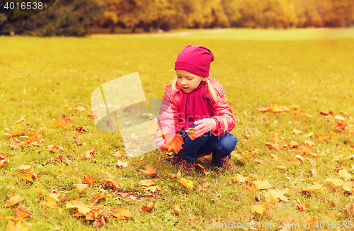 Image of happy little girl colecting autumn maple leaves