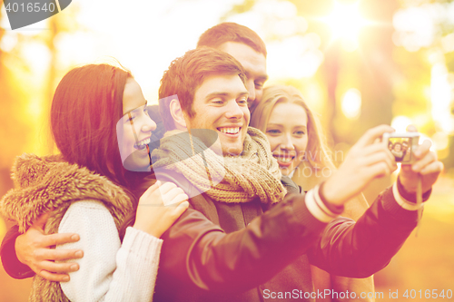 Image of group of friends with photo camera in autumn park