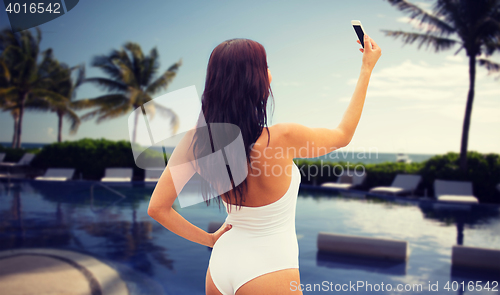 Image of young woman taking selfie with smartphone on beach