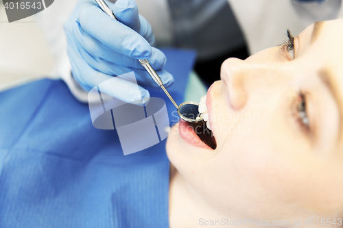 Image of close up of dentist examining female patient teeth