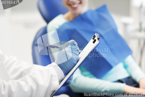 Image of close up of dentist with clipboard and patient