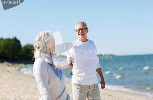 Image of happy senior couple holding hands on summer beach