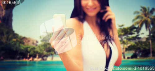 Image of young woman taking selfie with smartphone on beach