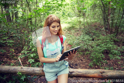 Image of happy woman with backpack and tablet pc in woods