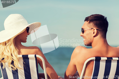 Image of happy couple sunbathing in chairs on summer beach