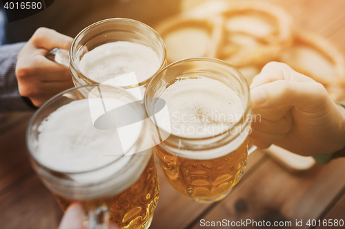 Image of close up of hands with beer mugs at bar or pub