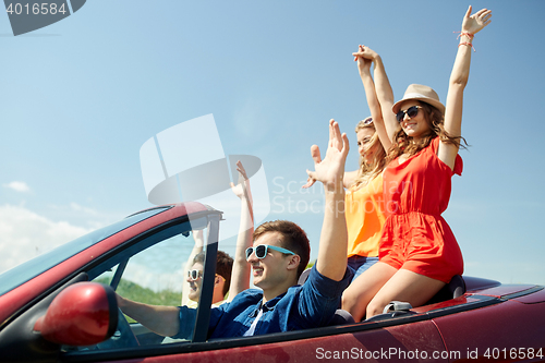 Image of happy friends driving in cabriolet car at country