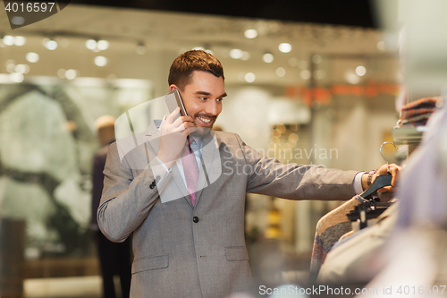 Image of happy man calling on smartphone at clothing store