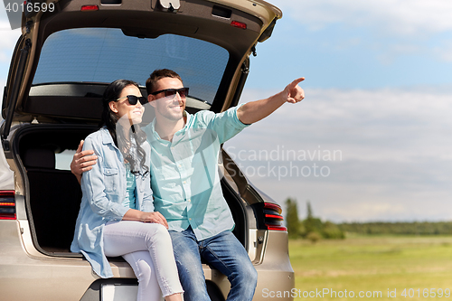 Image of happy couple hugging at open hatchback car trunk