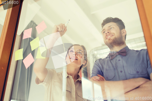 Image of happy creative team writing on blank office glass