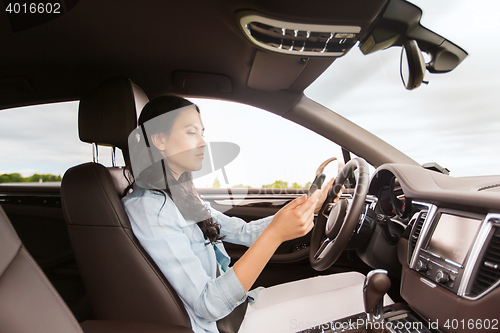 Image of woman driving car with smarhphone