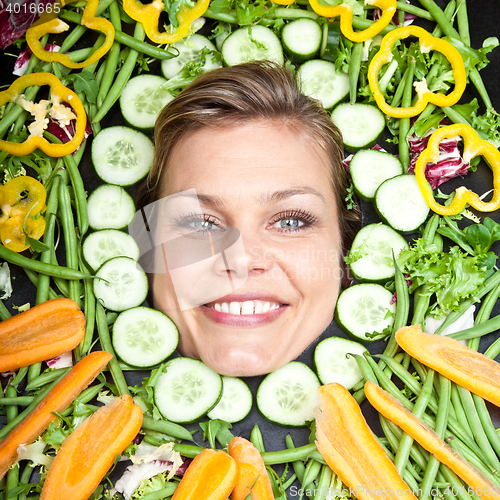 Image of Cute blond girl shot in studio with vegetables aroound the head