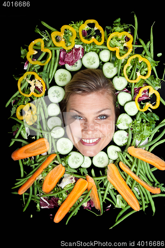 Image of Cute blond girl shot in studio with vegetables aroound the head