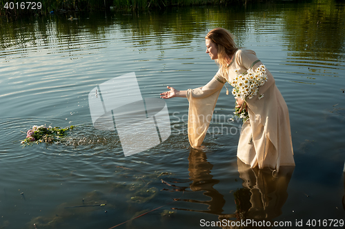 Image of Attractive woman lowers wreath in water