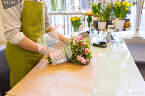 Image of florist wrapping flowers in paper at flower shop