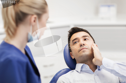 Image of female dentist and male patient with toothache