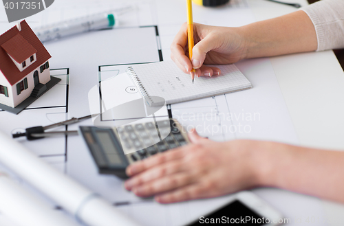 Image of close up of hand on blueprint writing to notebook